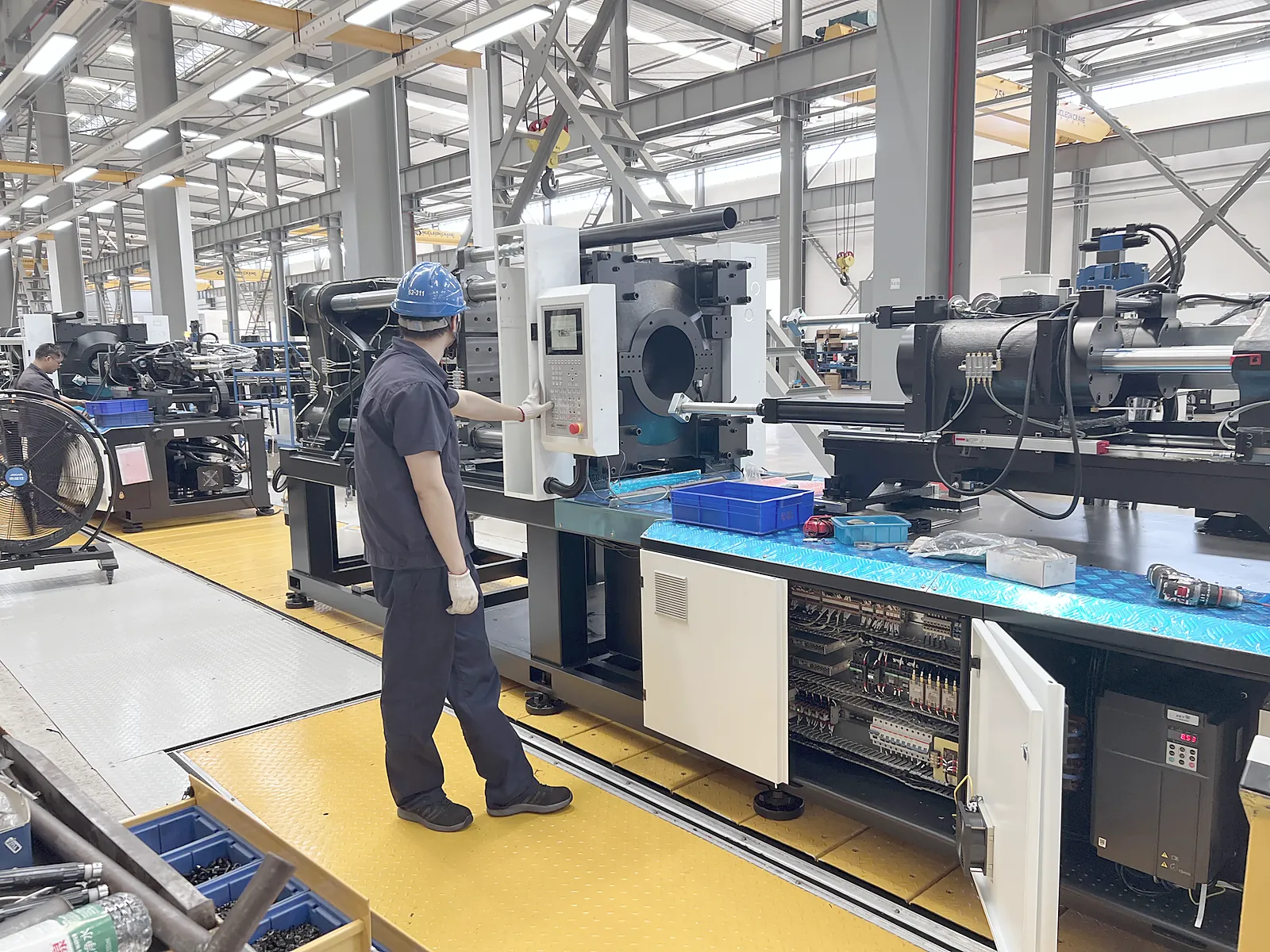 Technician checking an injection molding machine at HWAMDA